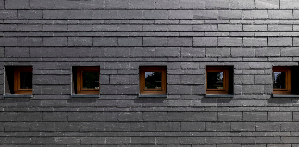 Plan rapproché du revêtement moderne CUPACLAD sur la façade rénovée de l'école Saint-Martin à Villers-le-Bouillet, illustrant la précision des finitions et l'alliance de l'innovation et du design contemporain